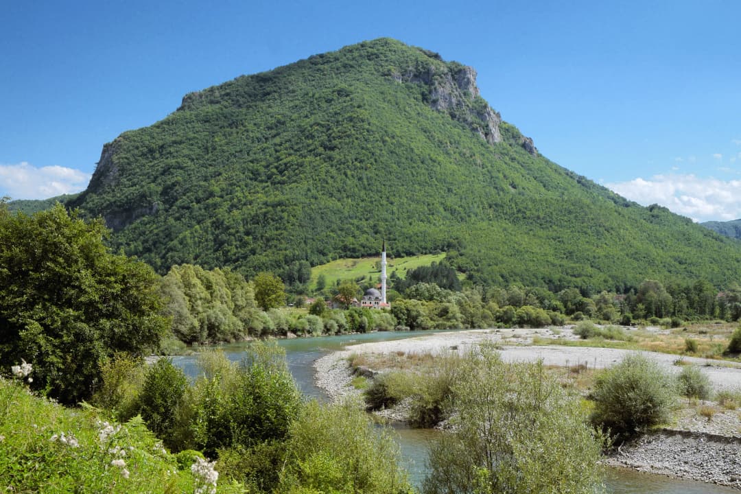 River bend and mosque beneath a wooded hill in the wider Bijelo Polje area