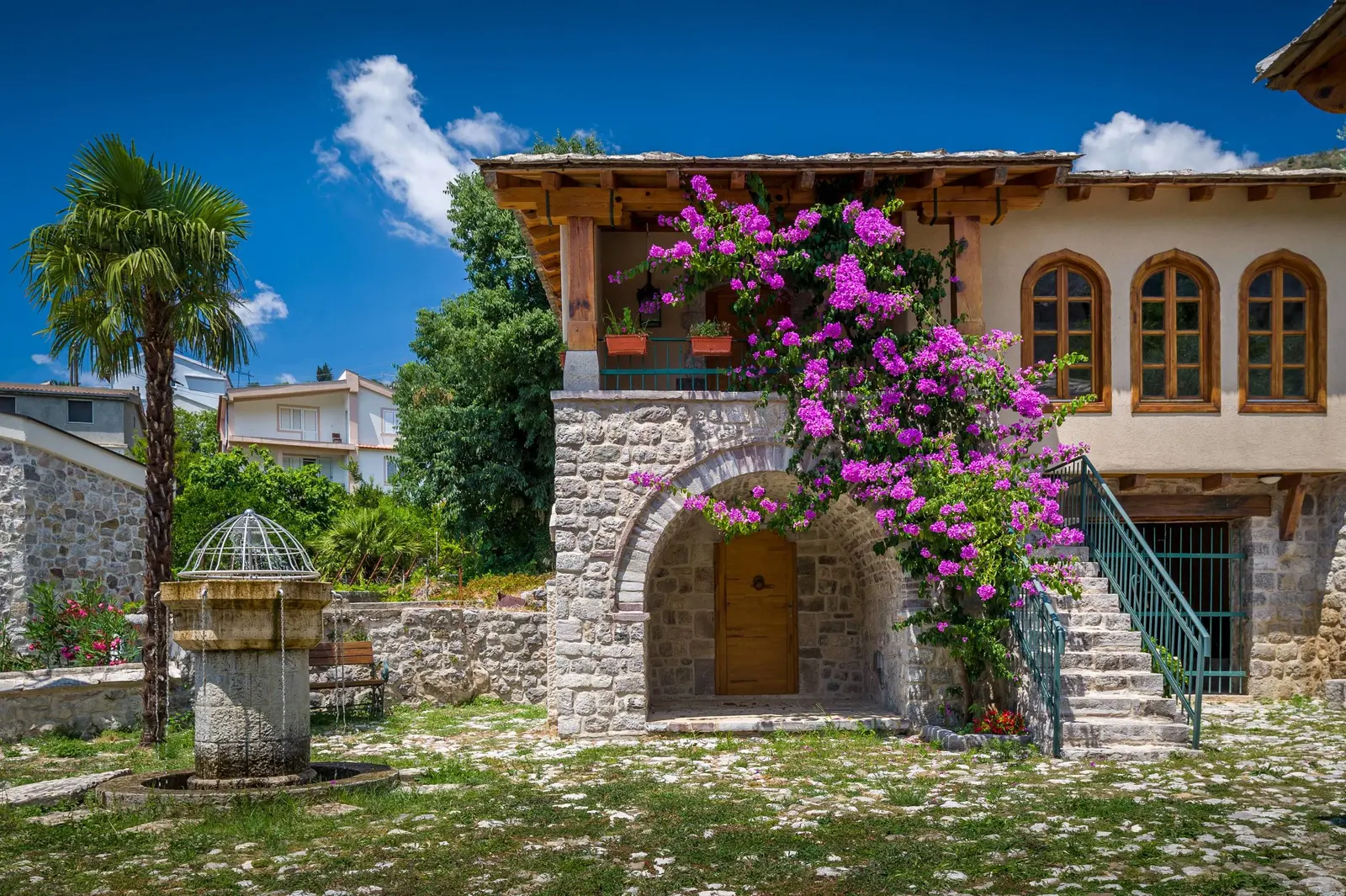 Restored stone house, courtyard fountain and bougainvillea inside Stari Bar