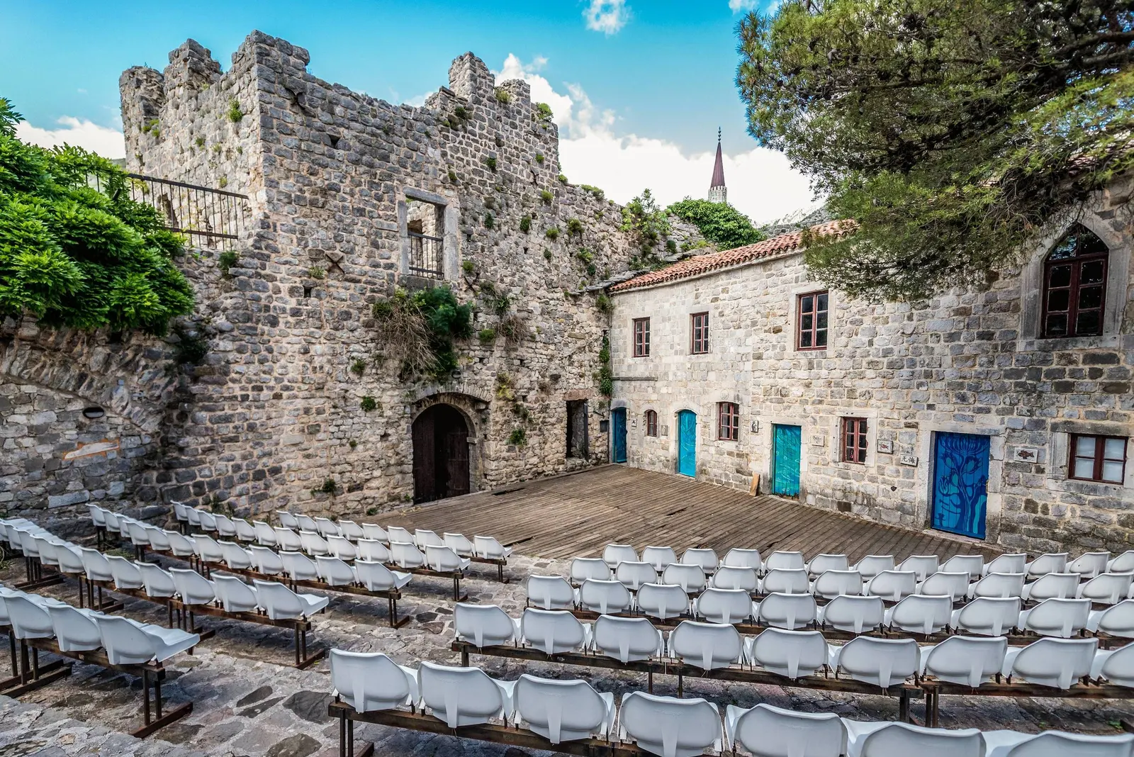 Open-air summer stage arranged among restored stone buildings in Stari Bar