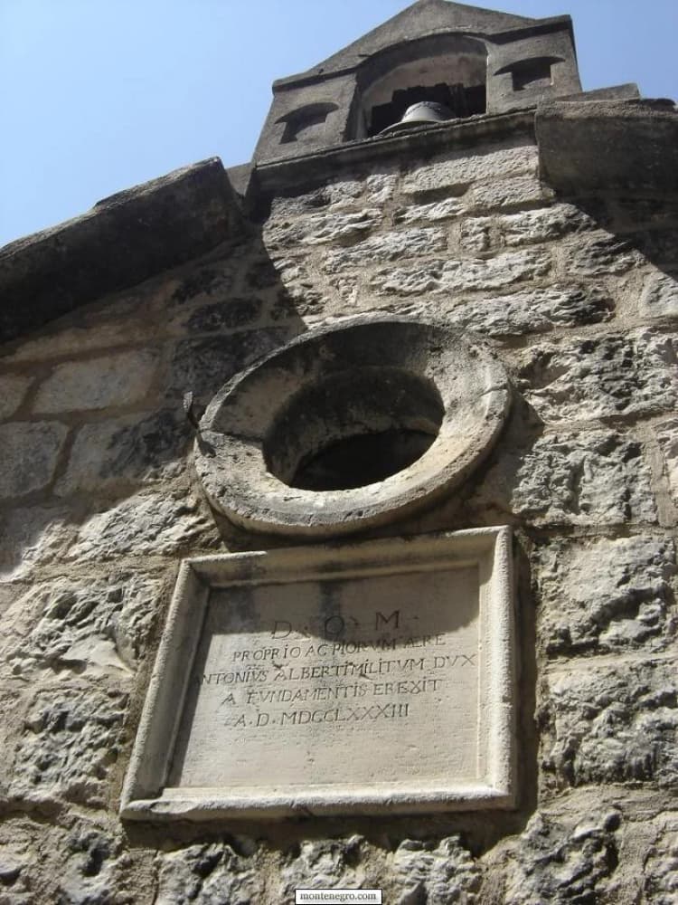 Stone church facade with an inscription and bell in Rose