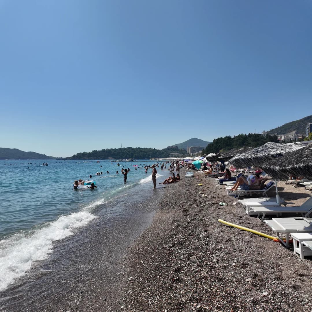 Redovi ležaljki poređani na šljunkovitoj obali plaže Bečići.