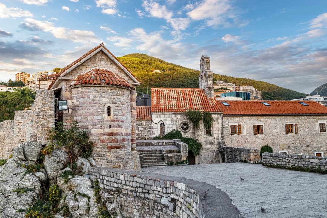 Crkveni kutak budvanskog Starog grada: zaobljena kamena apsida Santa Marije in Punta, a iza zvonik crkve Svetog Ivana.