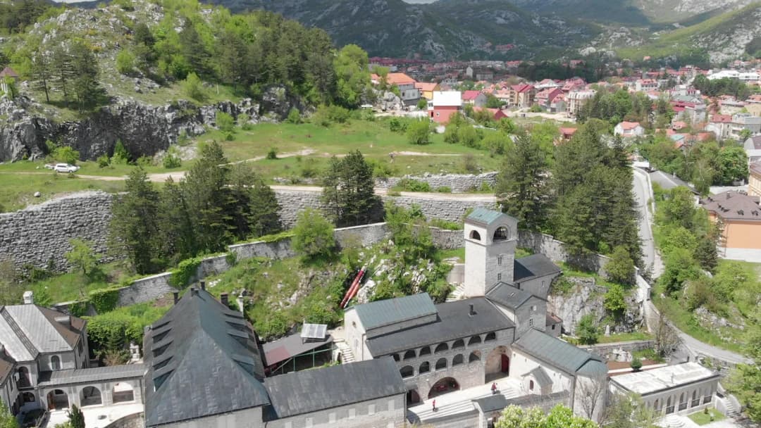 Cetinje rasuto po ravnoj kotlini okruženoj planinama, sa niskim krovovima staroga grada pod golim kraškim padinama.