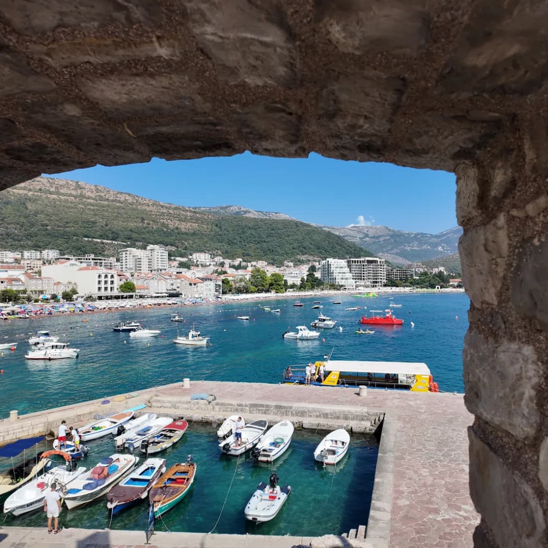 Kameni luk u tvrđavi koji uokviruje marinu u daljini.