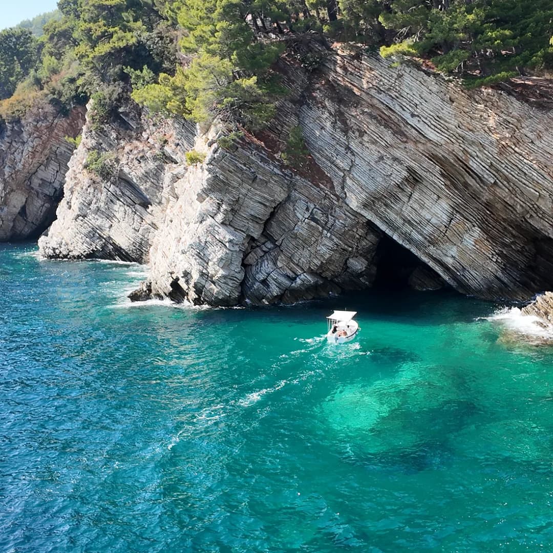 Mali čamac pod visokim stijenama, na ulazu u morsku pećinu.