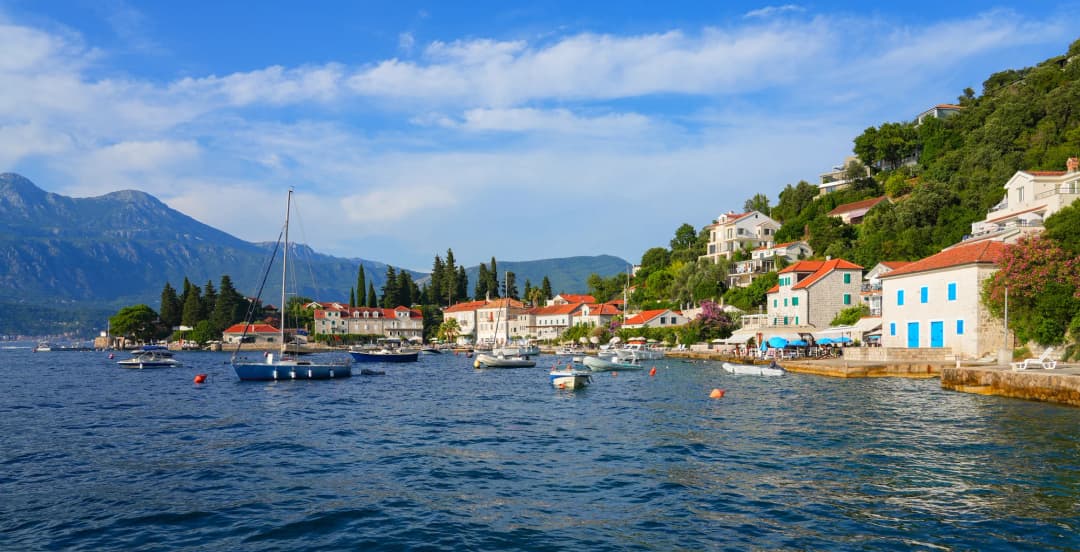 Rose harbour with small boats, stone houses and mountains across the bay