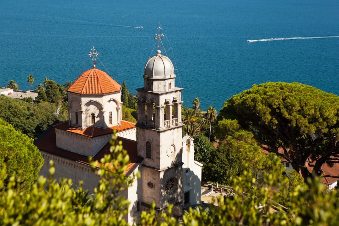 The domes and bell tower of Savina Monastery above the blue of the Bay of Kotor