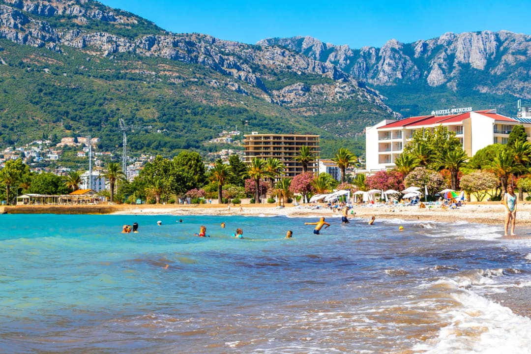Swimmers at Šušanj beach in Bar with the Rumija mountains rising behind