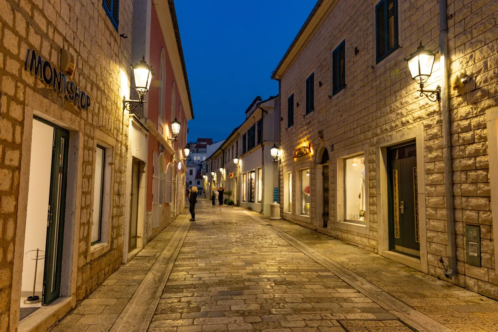 A lantern-lit pedestrian street in Herceg Novi Old Town at blue hour