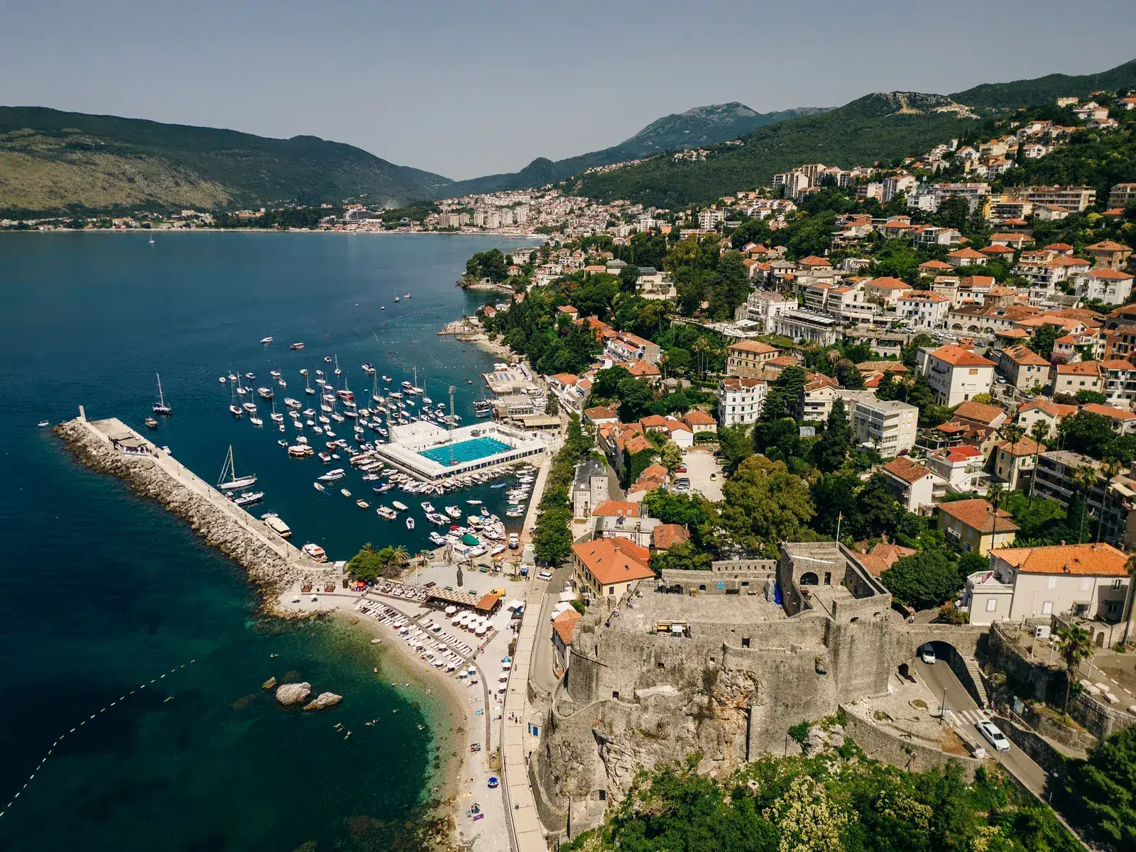 Stara kamena jezgra Herceg Novog uzdiže se nad zalivom, s krovovima od crijepa i crkvenim zvonikom među terasama.