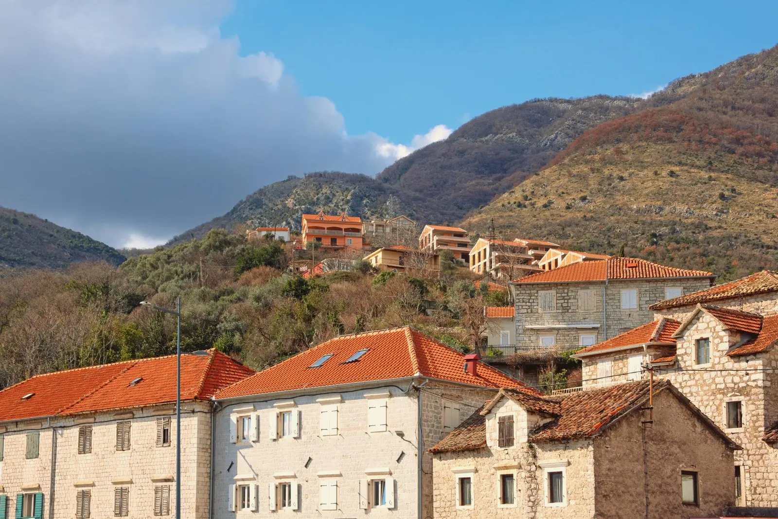 Kamene kuće uz obalu u Kamenarima ispod strme planinske padine