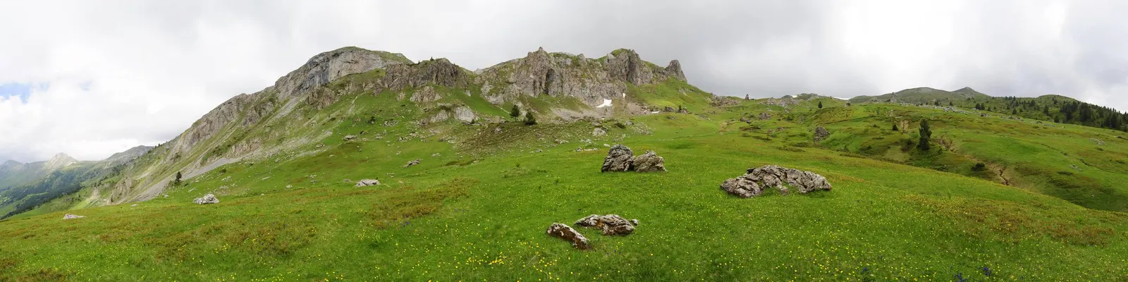 Široka planinska livada ispod razlomljenog stjenovitog grebena