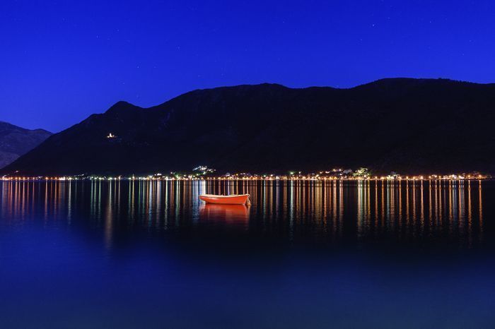 Photo of Sunset over Kotor Bay, with the lit-up church on the hill in the background.